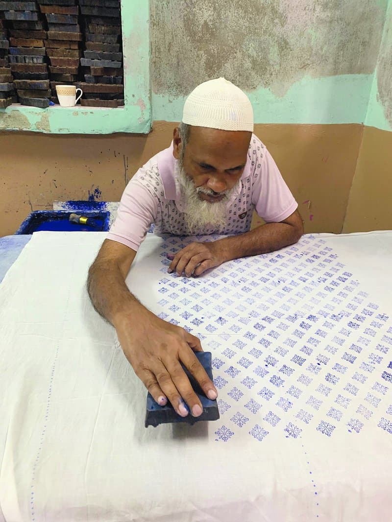 The chhipa (block printer) dips the carved woodblock into a tray of a neel, amber/gum and water solution and prints the design on the fabric.