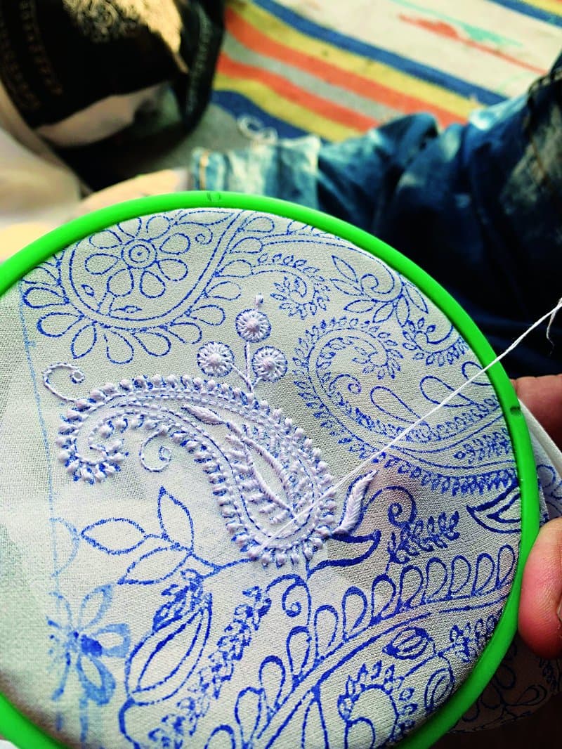 The women kaarigars follow the imprints as they embroider.