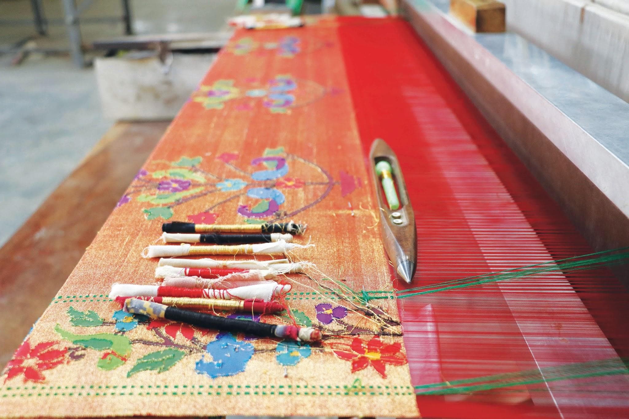 Weavers manually intertwine coloured weft threads with tiny bamboo spindles called kandis onto fine silk yarn and pure silver or gold zari